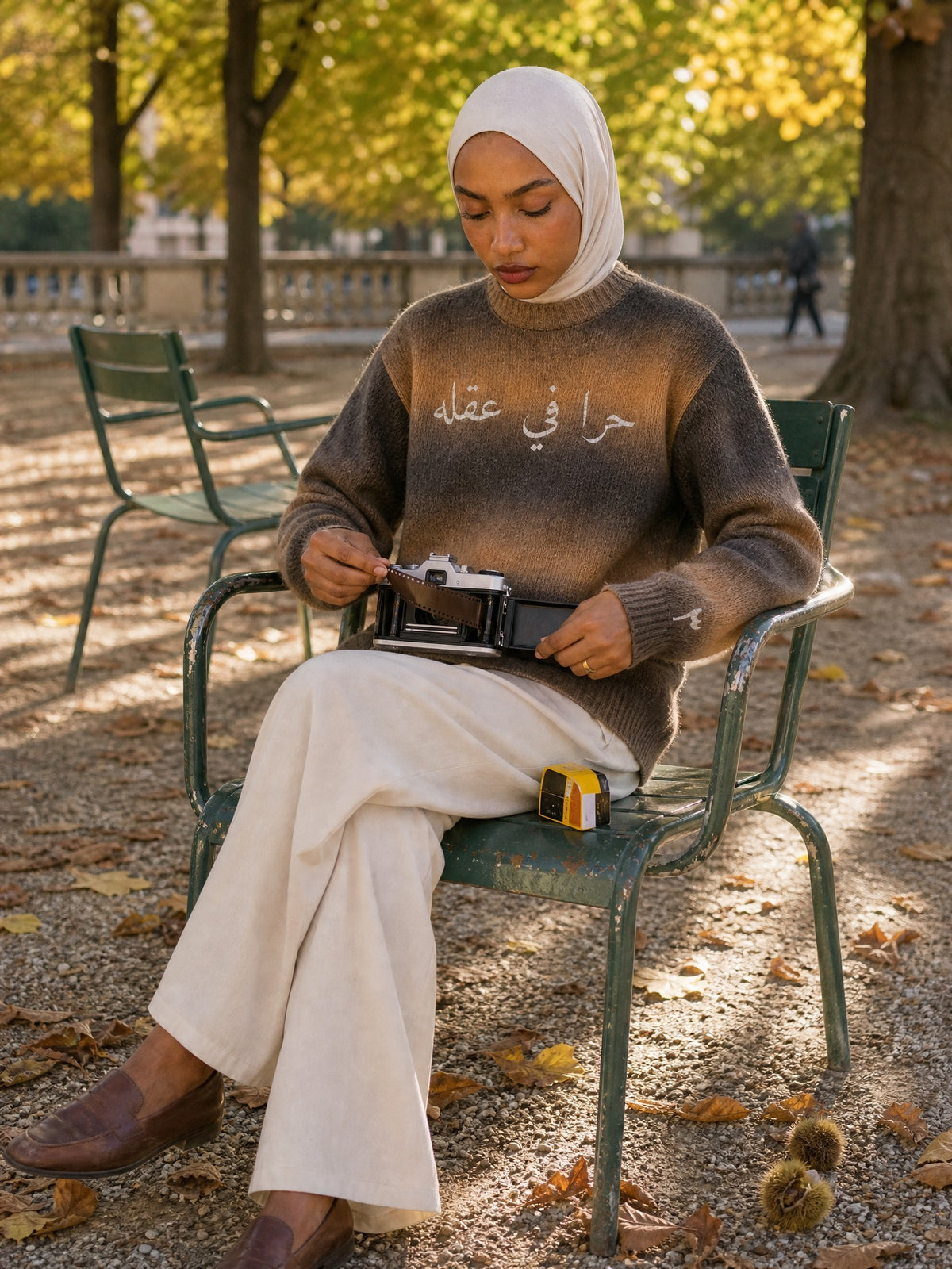 Amina im SYRVAIN «حرا» Strickpullover Braun legt einen Film ein, Jardin du Luxembourg